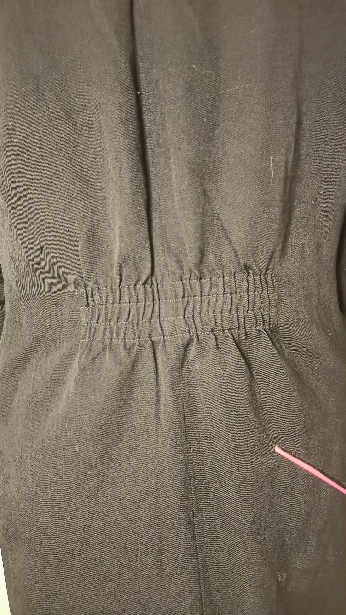 chemise/veste noire, au style épuré et intemporel, est sublimée par son discret passepoil rose sur la poche.