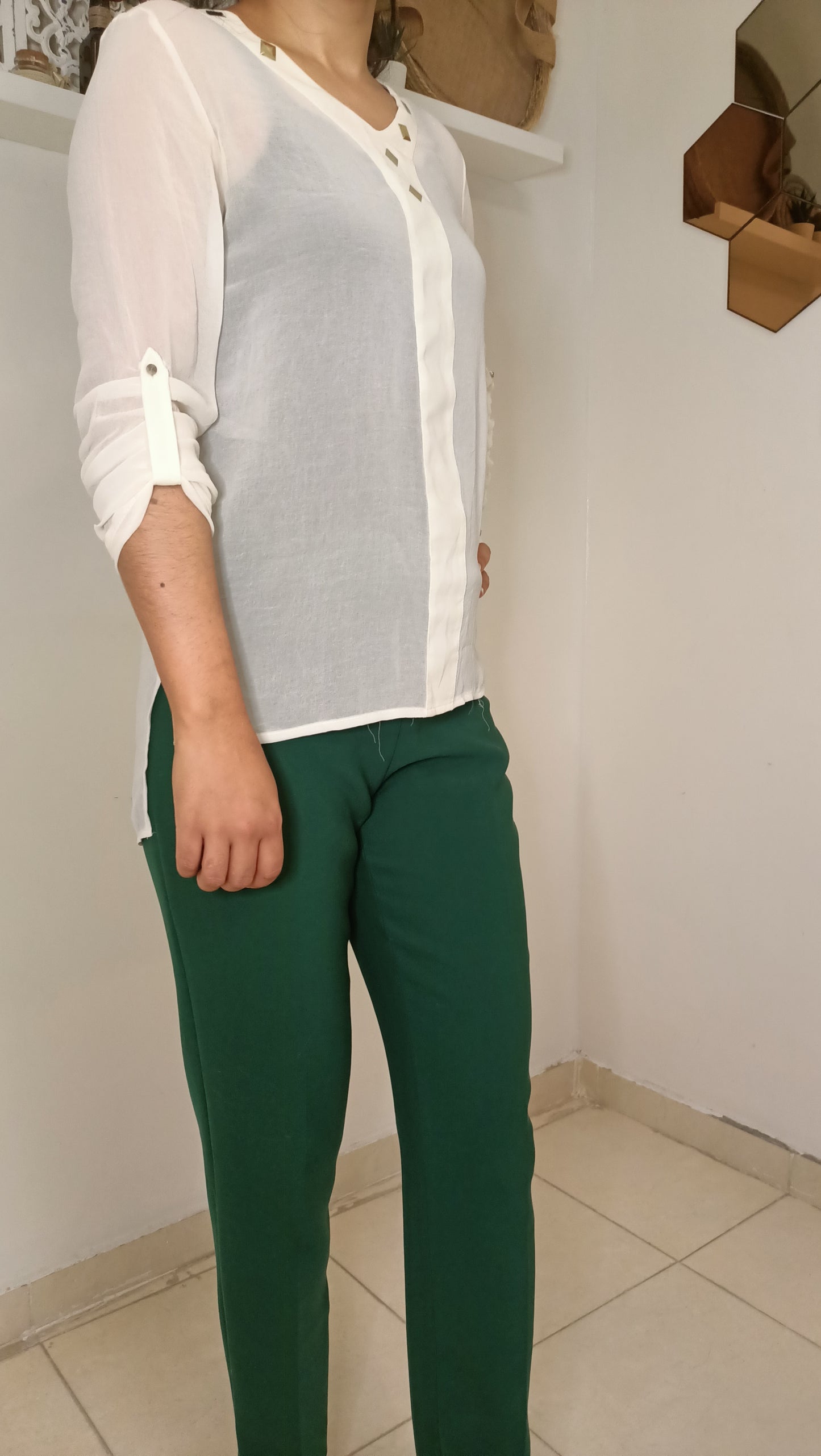 blouse fluide écrue aux détails dorés et ce pantalon vert émeraude créent un look à la fois élégant et décontracté.