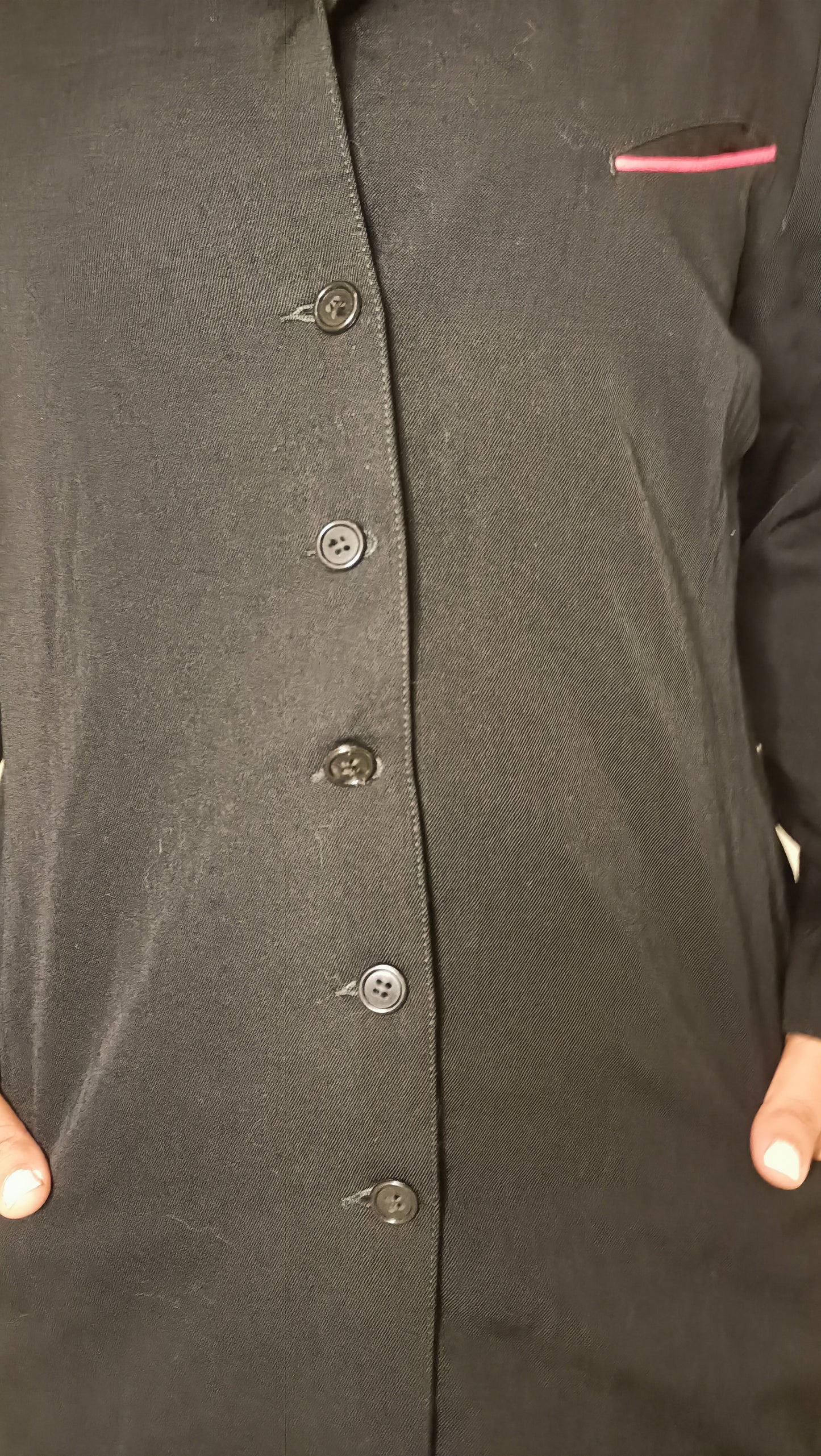 chemise/veste noire, au style épuré et intemporel, est sublimée par son discret passepoil rose sur la poche.