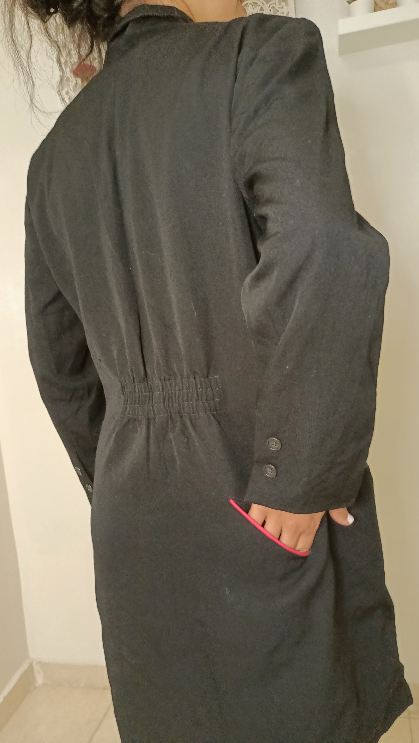 chemise/veste noire, au style épuré et intemporel, est sublimée par son discret passepoil rose sur la poche.